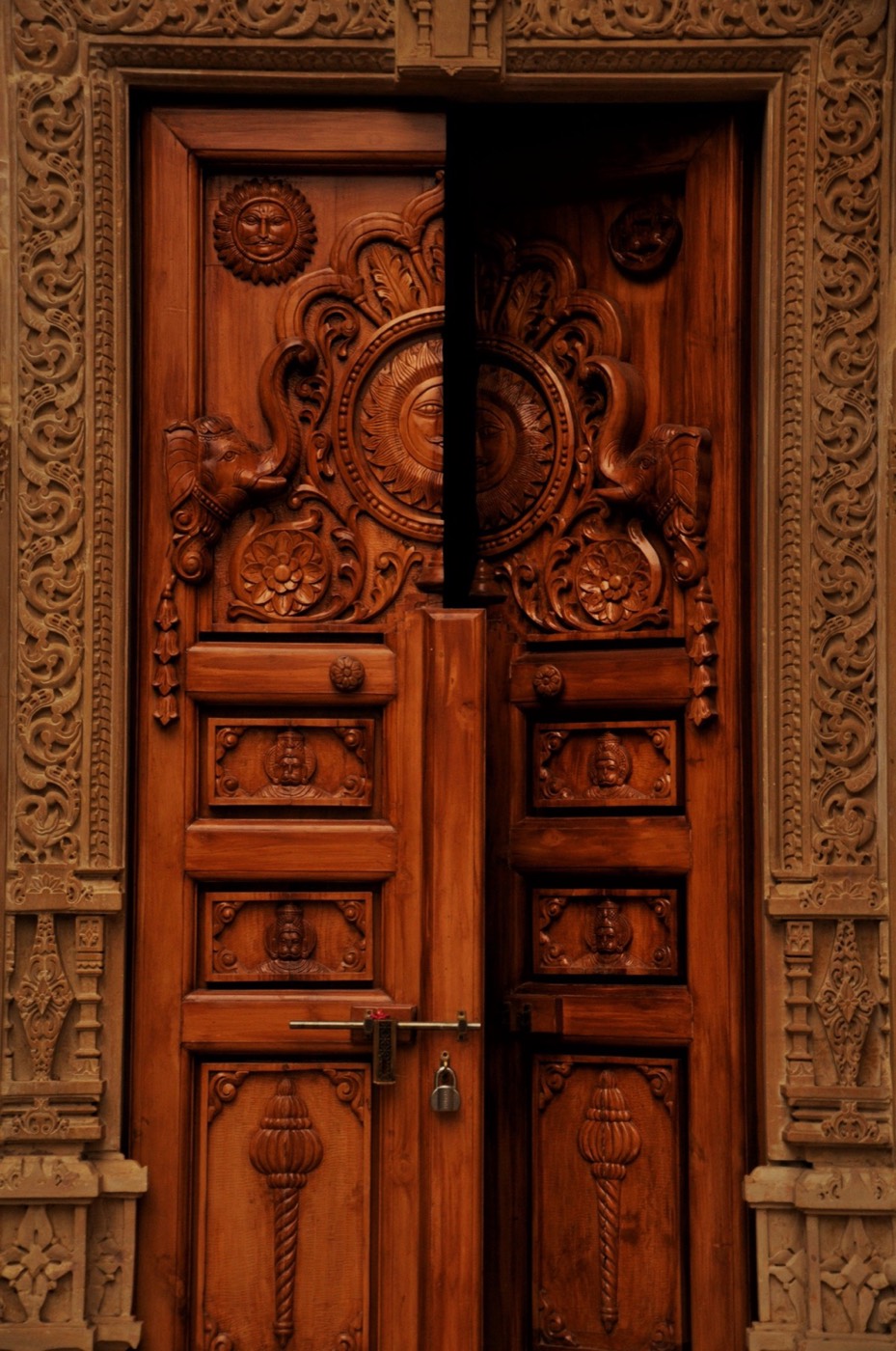 A traditional South Indian timber door with deeply carved panels and surround