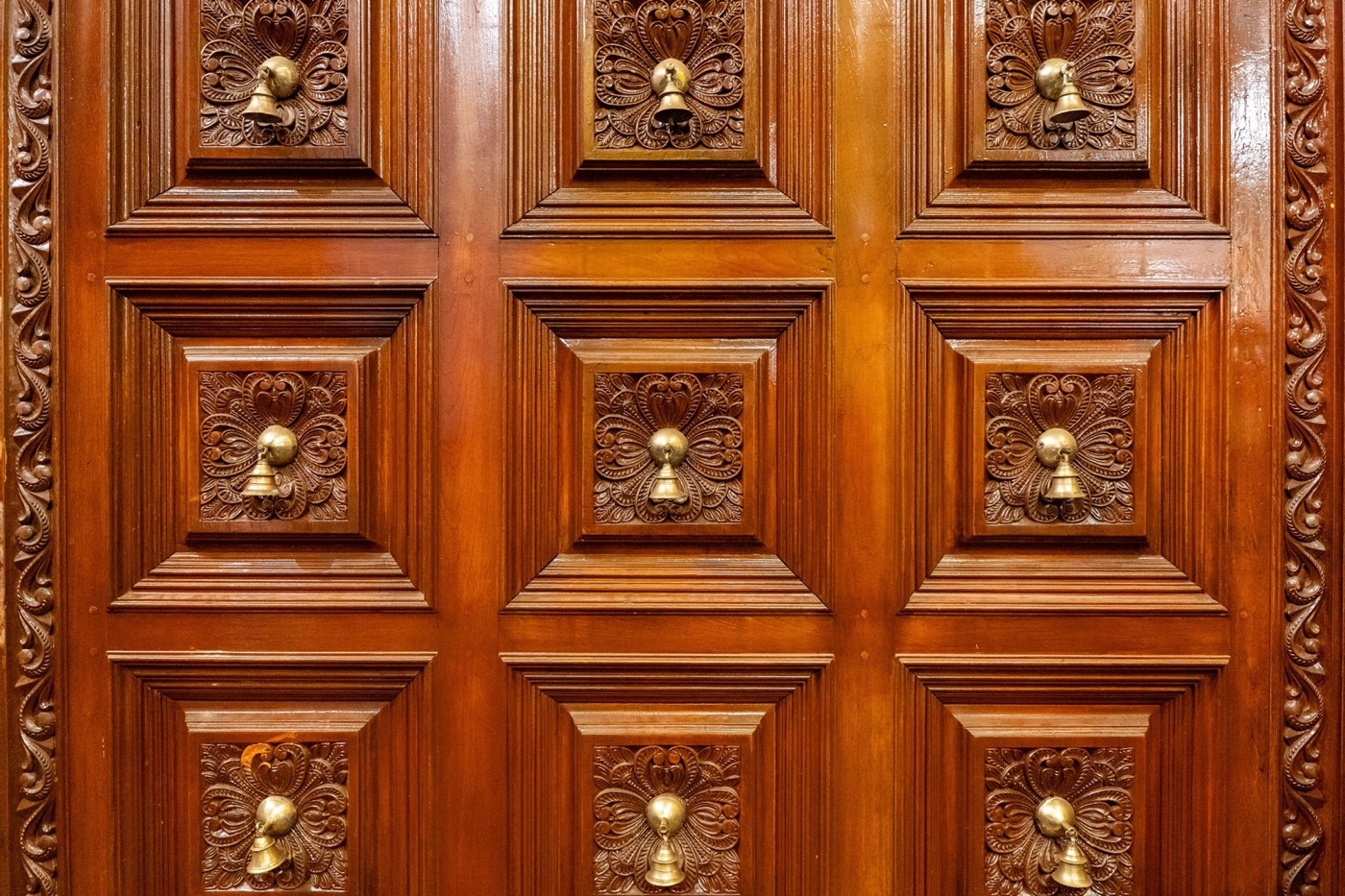 Close view of a carved and panelled timber door with brass fittings