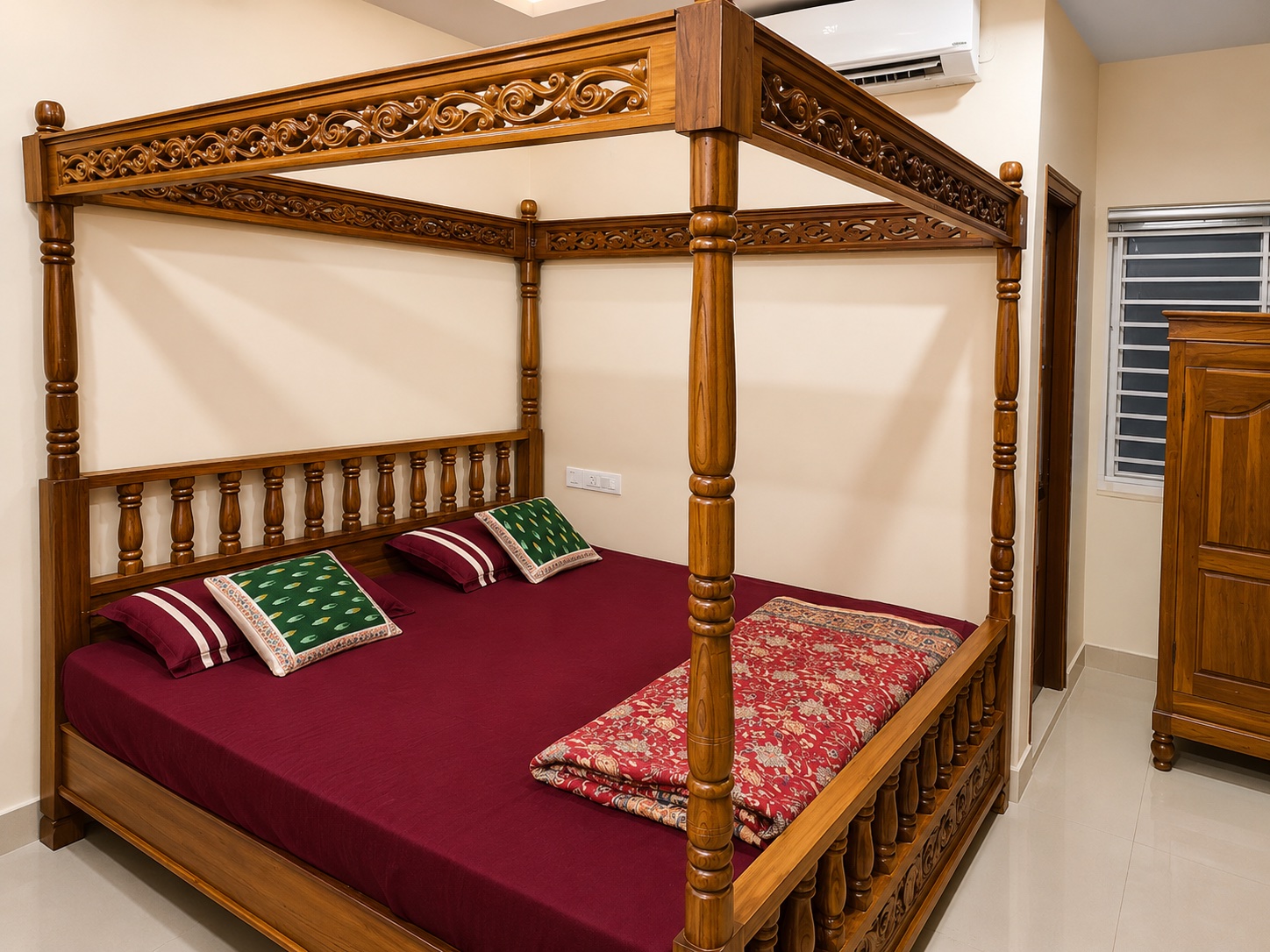 A carved four-poster teak bed with turned posts and a pierced canopy rail, in a family bedroom