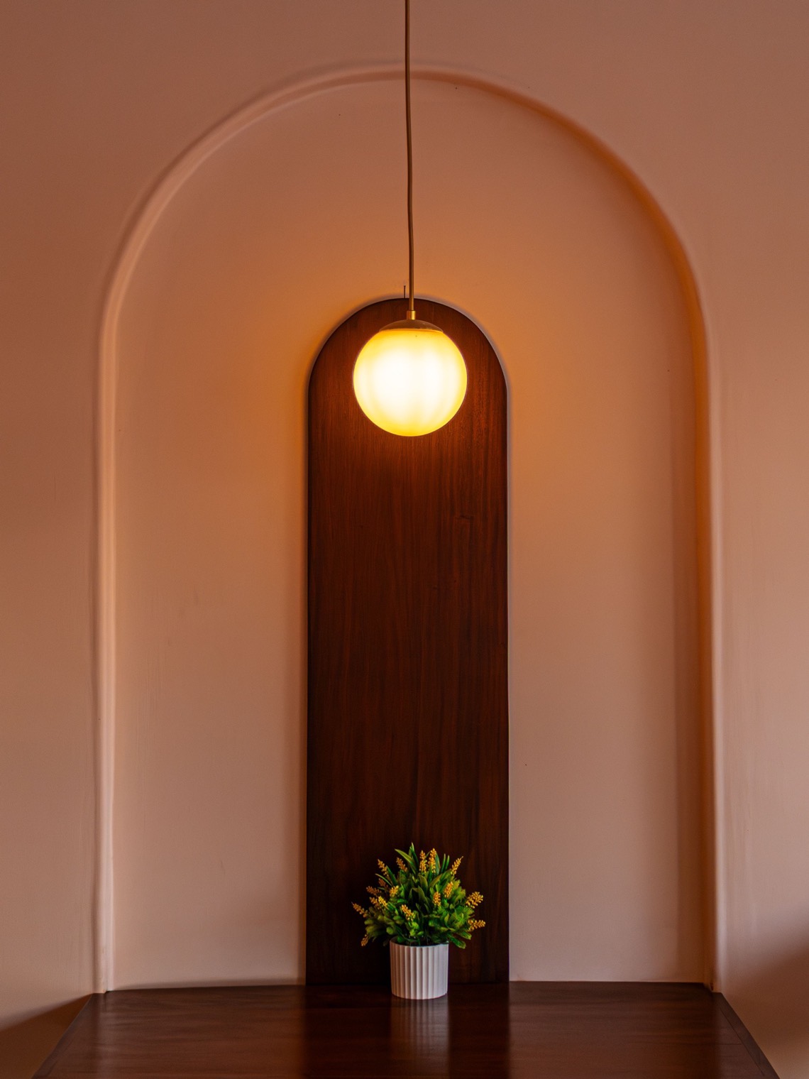A timber shelf set into a plastered alcove with a pendant light above