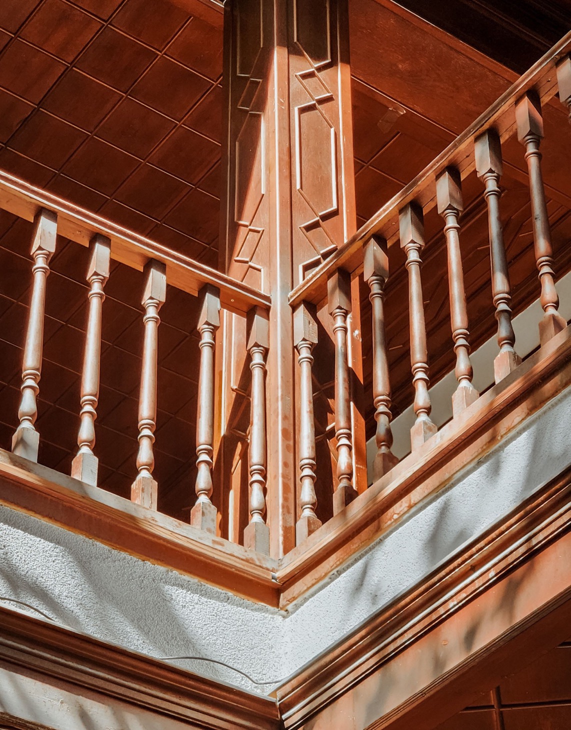 Turned timber balusters beneath a panelled ceiling in warm light