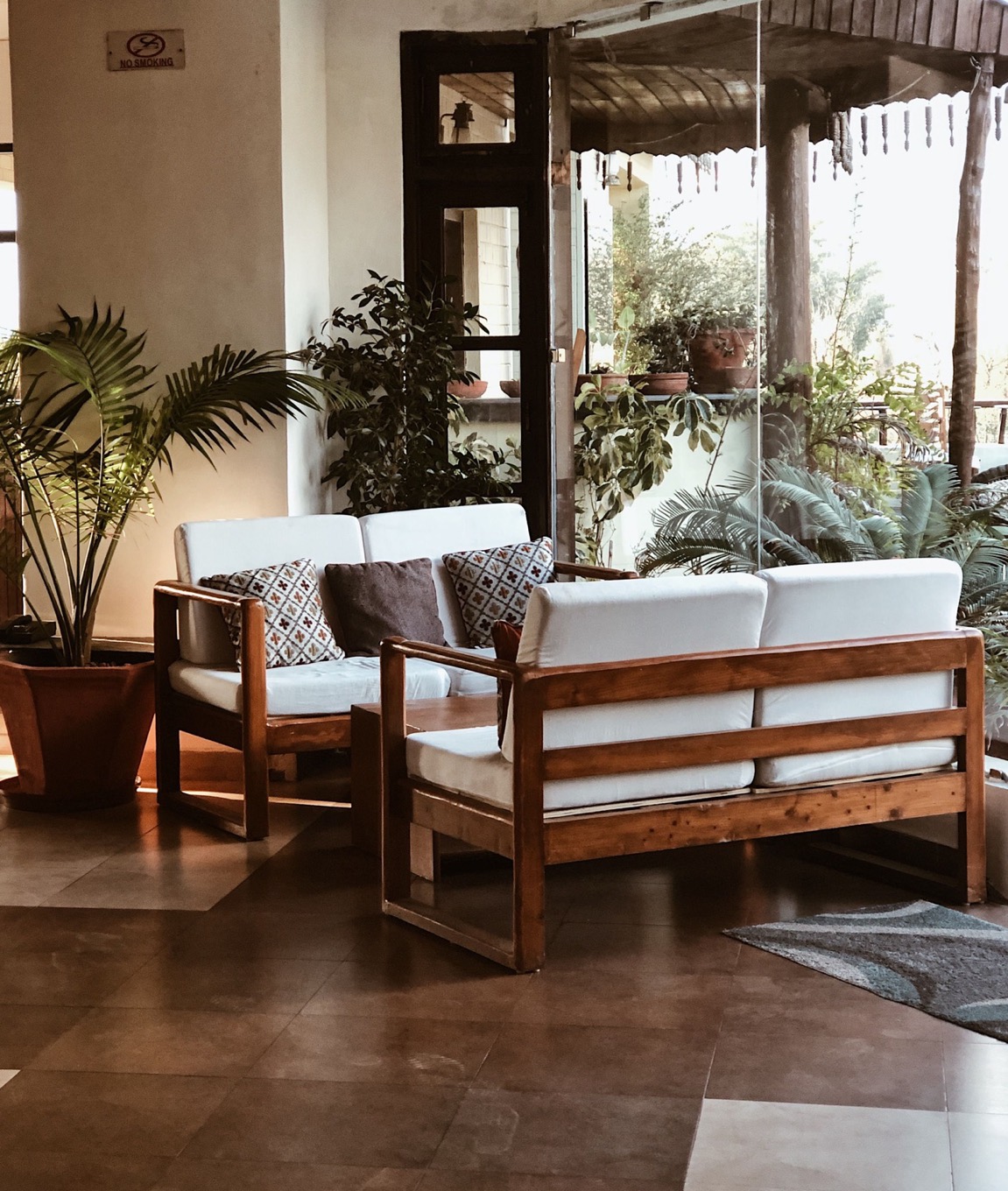 Teak-framed seating with pale cushions on a shaded verandah
